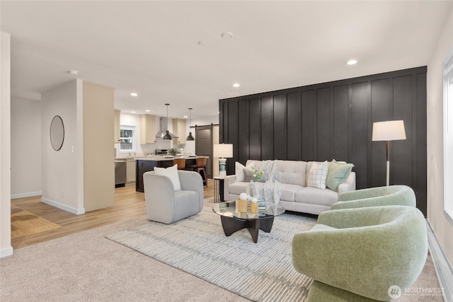 living room featuring light wood-style flooring, baseboards, recessed lighting, and light colored carpet