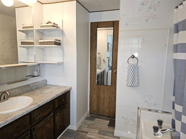 full bath with a bathing tub, a shower with curtain, baseboards, wood finished floors, and vanity