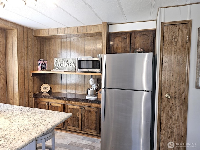 kitchen with light wood finished floors, open shelves, wood walls, and stainless steel appliances