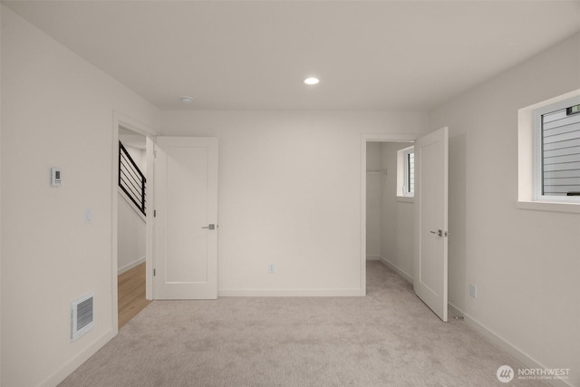 spare room with light carpet, recessed lighting, visible vents, and baseboards