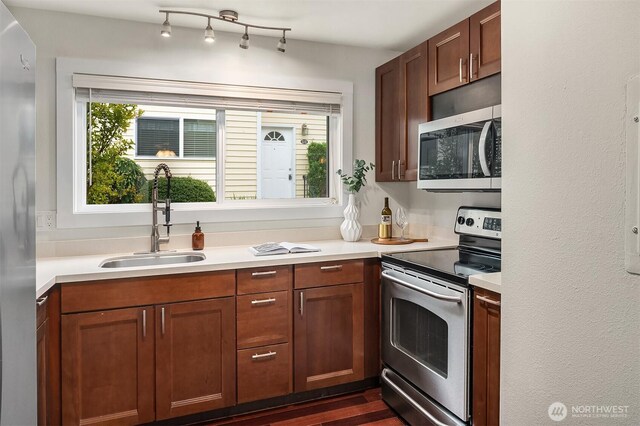 kitchen featuring a sink, light countertops, stainless steel appliances, and a healthy amount of sunlight
