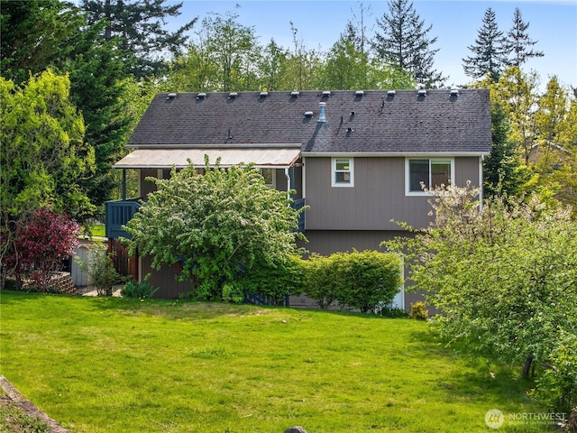 back of property featuring a lawn and a shingled roof