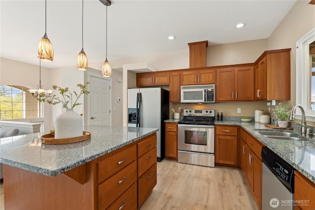 kitchen featuring a sink, appliances with stainless steel finishes, brown cabinetry, and light wood-style floors