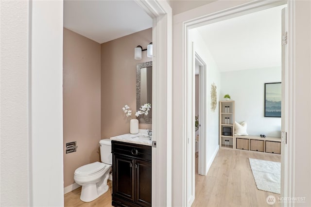 bathroom featuring vanity, baseboards, wood finished floors, and toilet