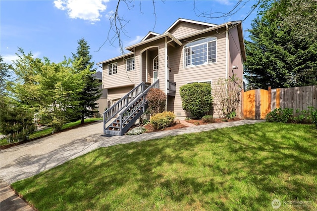 raised ranch featuring fence, a front lawn, and stairway