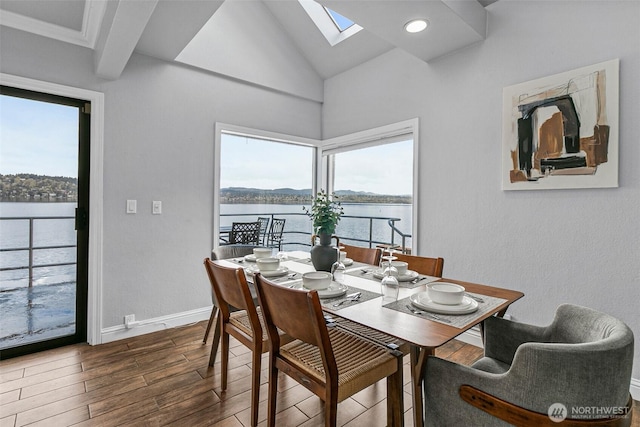 dining space with dark wood finished floors, baseboards, a water view, and plenty of natural light