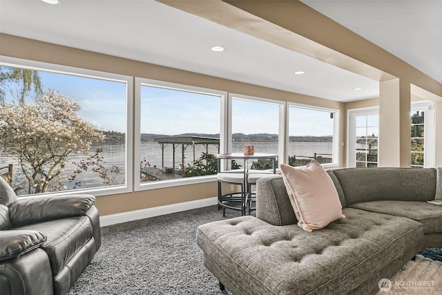 living room featuring carpet, baseboards, a water view, and recessed lighting