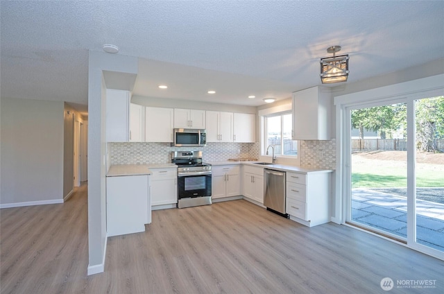 303 Alder Ln N, Pacific, WA 98047 - kitchen with light wood-type flooring, light countertops, backsplash, white cabinets, and stainless steel appliances