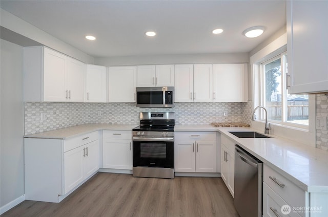 303 Alder Ln N, Pacific, WA 98047 - kitchen featuring tasteful backsplash, white cabinets, a sink, light wood finished floors, and stainless steel appliances