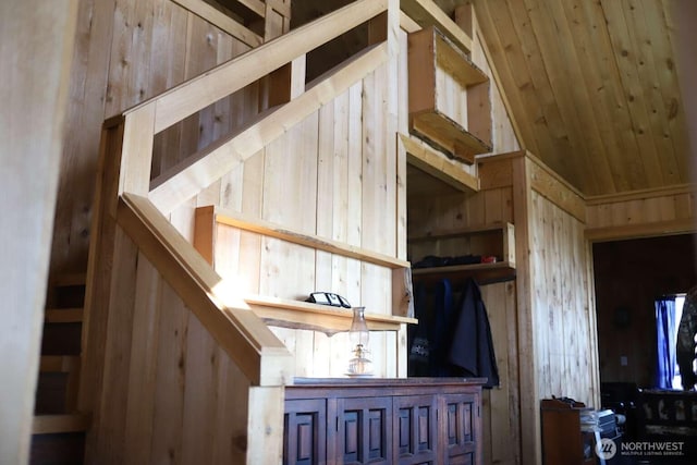 staircase with vaulted ceiling and wooden walls