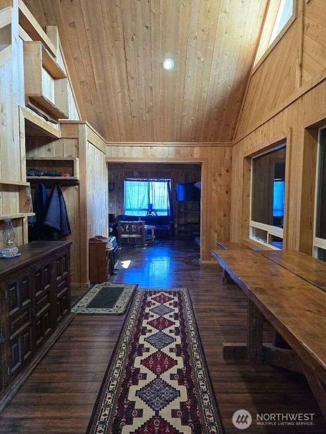 hallway featuring lofted ceiling, wooden ceiling, wood walls, and wood finished floors