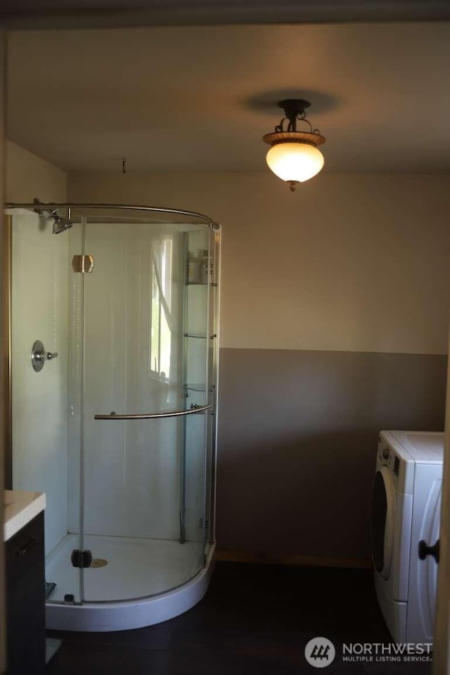 bathroom featuring washer / clothes dryer and a stall shower
