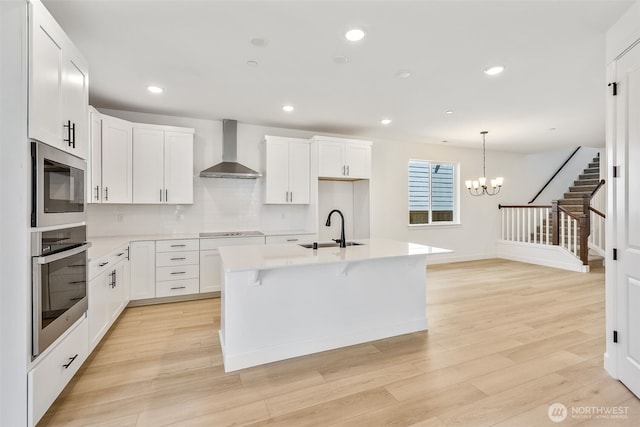 9705 205th St E Unit 29, Graham, WA 98338 - kitchen with an island with sink, wall chimney range hood, light countertops, a sink, and appliances with stainless steel finishes