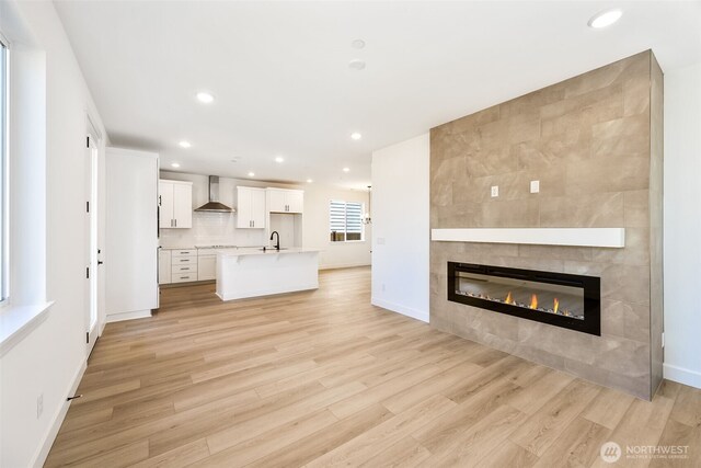 9705 205th St E Unit 29, Graham, WA 98338 - unfurnished living room featuring a tiled fireplace, light wood-style flooring, recessed lighting, and a sink