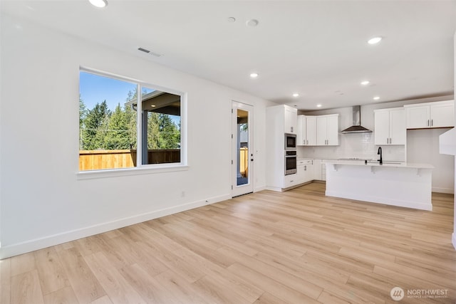 9705 205th St E Unit 29, Graham, WA 98338 - unfurnished living room featuring visible vents, a sink, baseboards, light wood-style floors, and recessed lighting