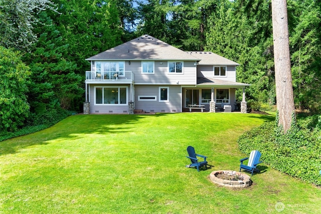 back of property featuring crawl space, a sunroom, a yard, an outdoor fire pit, and a balcony