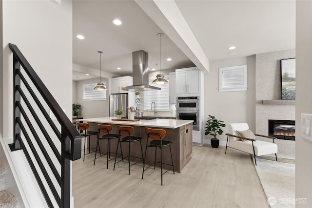 13362 NE 143rd Ct Unit 53, Woodinville, WA 98072 - kitchen featuring light wood-style floors, island exhaust hood, appliances with stainless steel finishes, and a kitchen breakfast bar