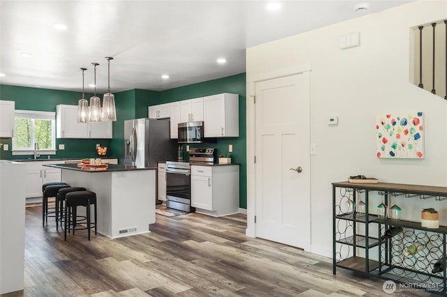 kitchen featuring dark countertops, wood finished floors, stainless steel appliances, and recessed lighting