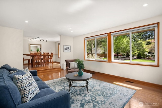 living room featuring visible vents, wood finished floors, and a wealth of natural light