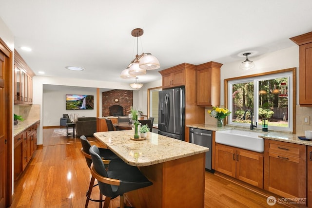 kitchen with stainless steel dishwasher, brown cabinetry, fridge with ice dispenser, a sink, and backsplash