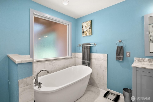 bathroom with vanity, marble finish floor, and a soaking tub
