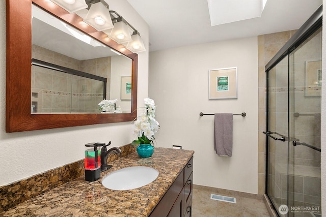 full bathroom with vanity, a stall shower, and visible vents