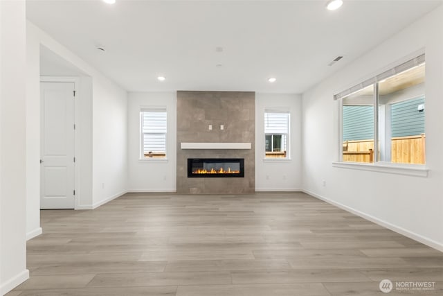 20519 97th Ave E Unit 26, Graham, WA 98338 - unfurnished living room with healthy amount of natural light, recessed lighting, light wood-type flooring, a tile fireplace, and baseboards