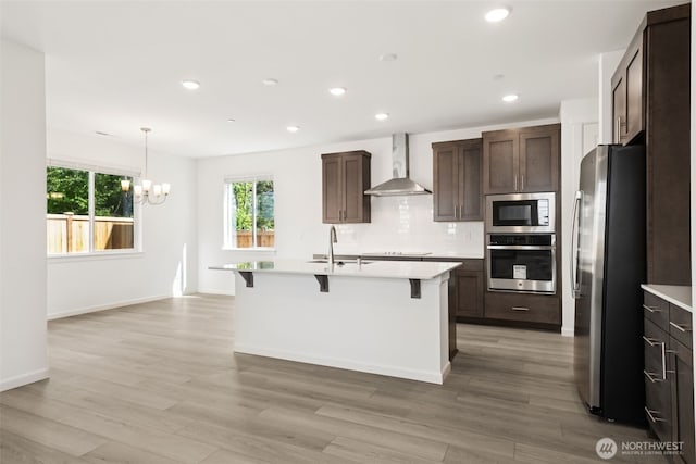 20519 97th Ave E Unit 26, Graham, WA 98338 - kitchen featuring stainless steel appliances, wall chimney range hood, a chandelier, light countertops, and a breakfast bar area