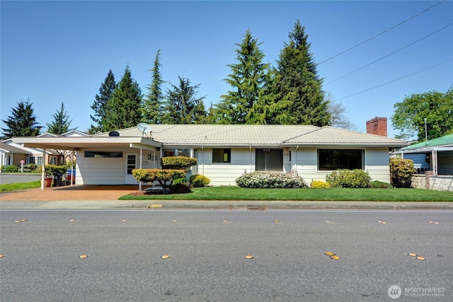 single story home with a chimney, a tiled roof, a carport, driveway, and a front yard