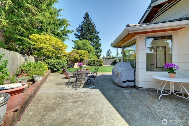 view of patio with area for grilling, outdoor dining area, and a fenced backyard