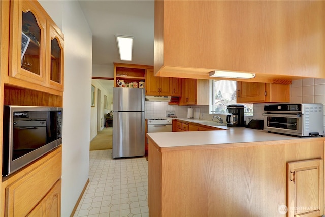 kitchen featuring built in microwave, under cabinet range hood, a peninsula, freestanding refrigerator, and light floors