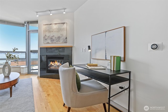 office area with a tile fireplace, track lighting, and wood finished floors