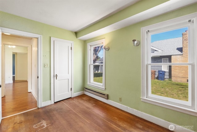unfurnished bedroom with baseboards, baseboard heating, and wood finished floors