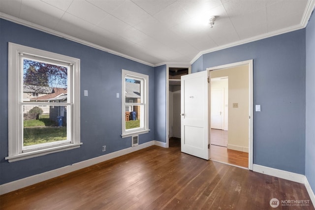 unfurnished bedroom with wood finished floors, visible vents, baseboards, and ornamental molding