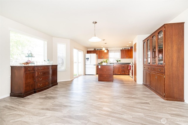 101 Holloway Dr, Chehalis, WA 98532 - kitchen featuring brown cabinetry, freestanding refrigerator, baseboards, hanging light fixtures, and a kitchen island