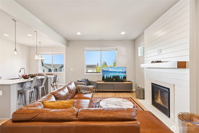 living room featuring recessed lighting, light wood-style floors, and a large fireplace