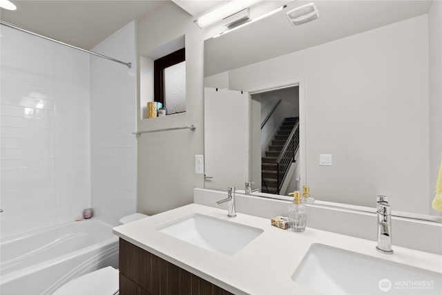 bathroom with washtub / shower combination, double vanity, a sink, and toilet