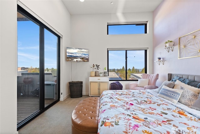 carpeted bedroom featuring access to outside, a high ceiling, baseboards, and multiple windows