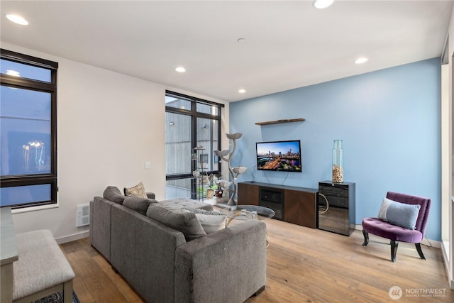 living area with recessed lighting, baseboards, visible vents, and hardwood / wood-style flooring