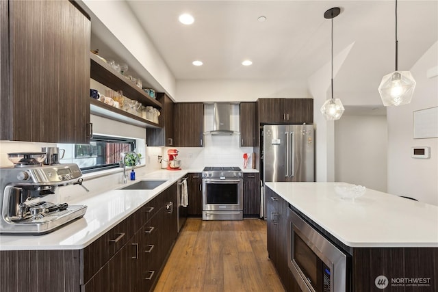 kitchen with dark brown cabinets, open shelves, wall chimney exhaust hood, appliances with stainless steel finishes, and a sink