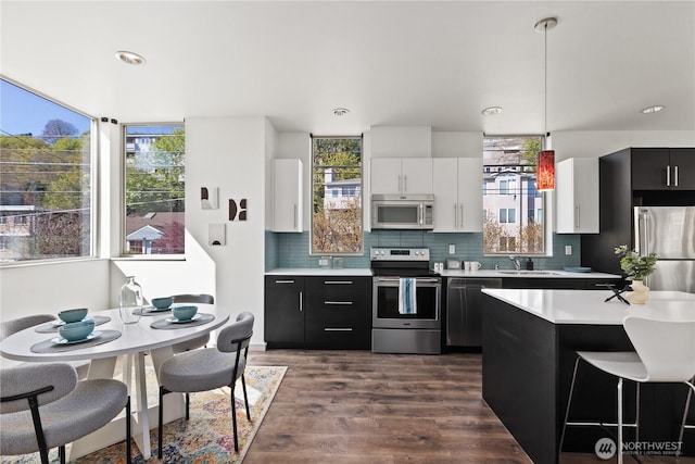 kitchen featuring stainless steel appliances, dark wood-style floors, tasteful backsplash, dark cabinets, and light countertops