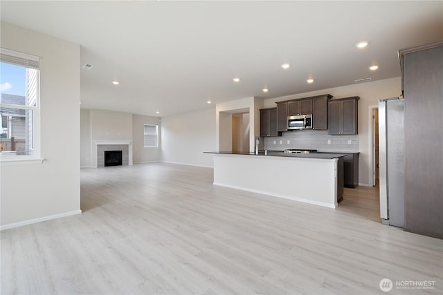 13509 197th St E, Graham, WA 98338 - kitchen with stainless steel appliances, open floor plan, dark brown cabinets, a sink, and light wood finished floors