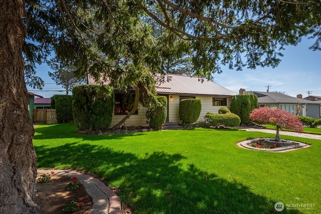 view of front of property with fence, a front lawn, and metal roof