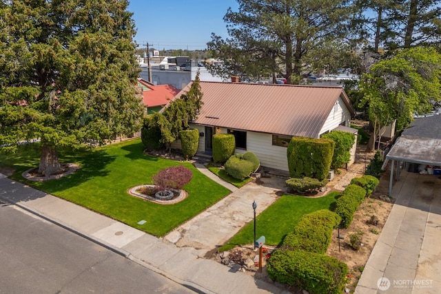 view of front of home featuring driveway, a front lawn, and metal roof