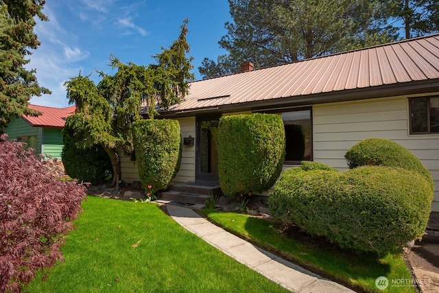 ranch-style home with a front lawn, a chimney, and metal roof