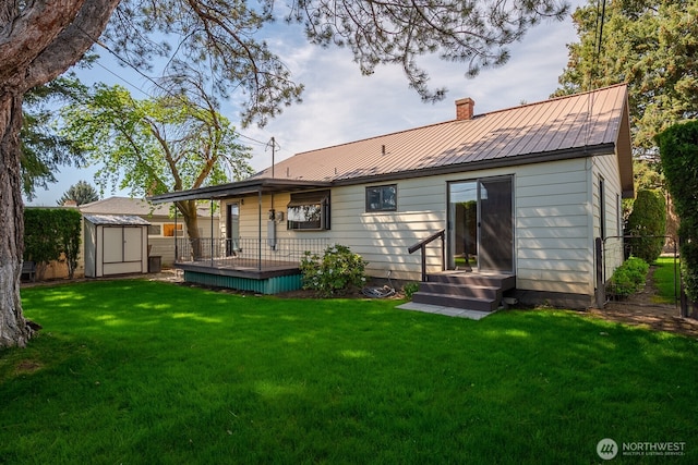 back of house featuring a chimney, an outbuilding, a yard, metal roof, and a storage unit