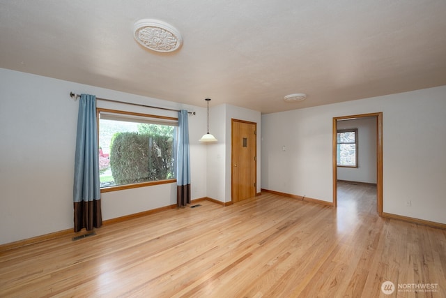 unfurnished room with light wood-type flooring, visible vents, and baseboards