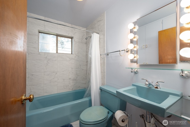 bathroom with shower / tub combo with curtain, toilet, and a sink