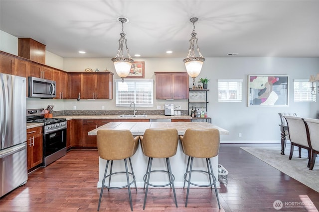 kitchen with a kitchen breakfast bar, a center island, a sink, light countertops, and stainless steel appliances