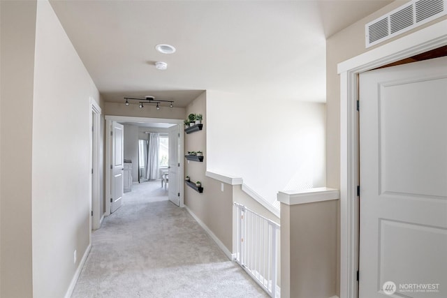 hallway with light colored carpet, baseboards, and visible vents